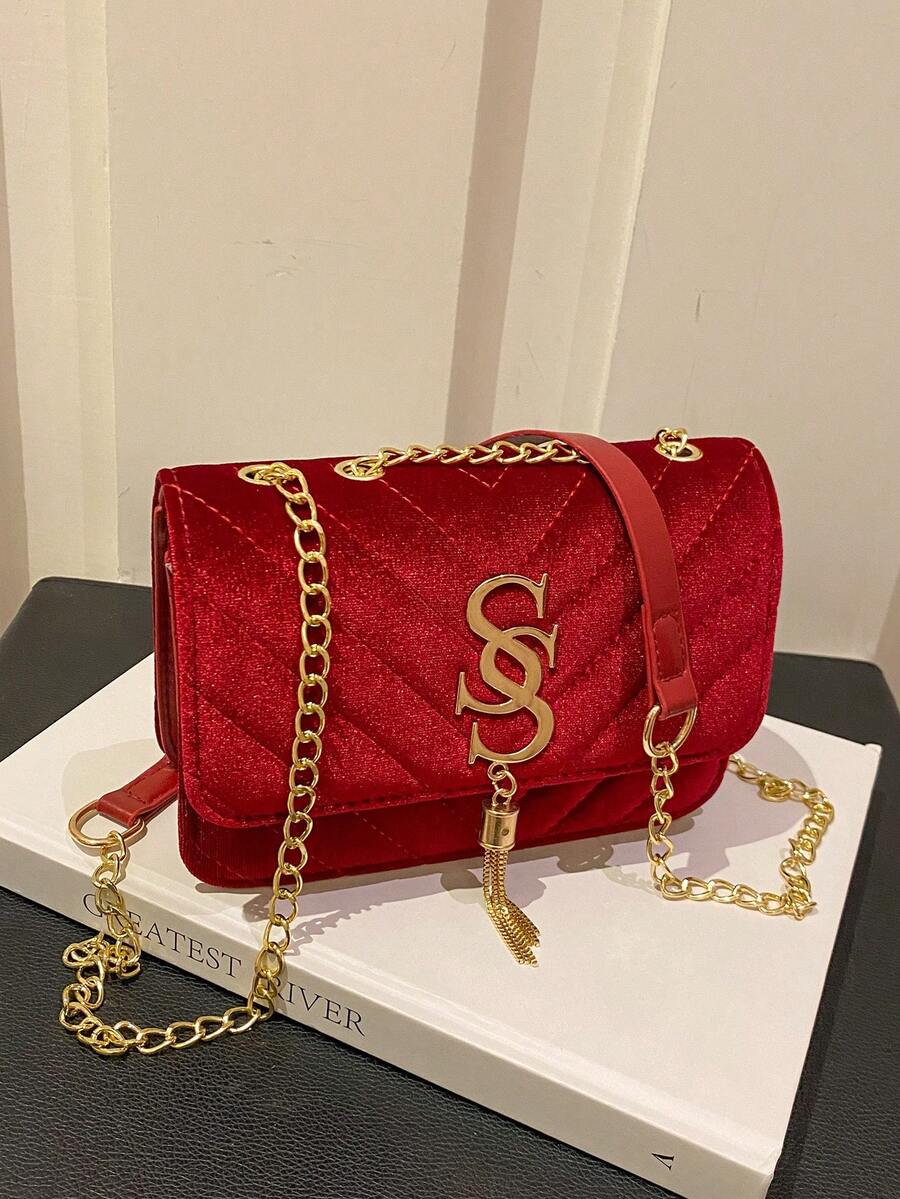 Refined Embossed Letter Shoulder Bag – New Year Collection in red with gold chain detail on a white book.