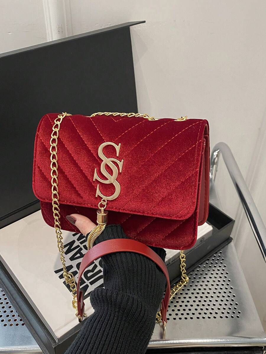 Refined Embossed Letter Shoulder Bag – New Year Collection in red held in a hand with a gold chain strap.