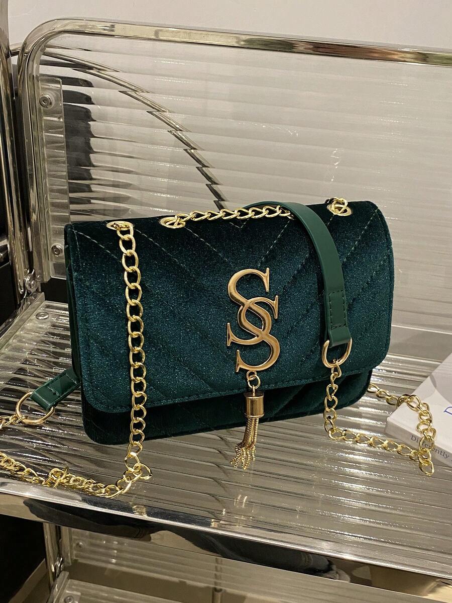 Refined Embossed Letter Shoulder Bag – New Year Collection on display with green velvet and gold chain.