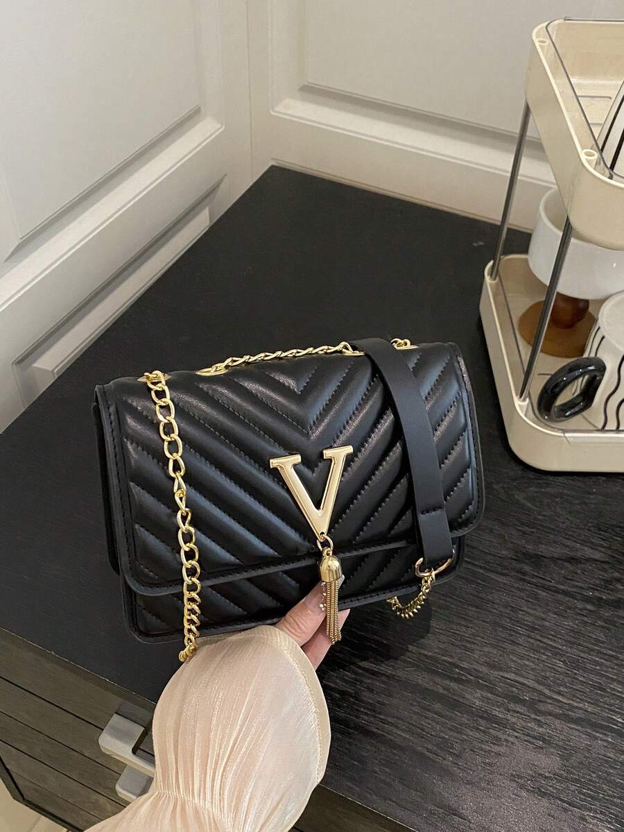 Refined Embossed Letter Shoulder Bag – New Year Collection in black with chain strap on a table.