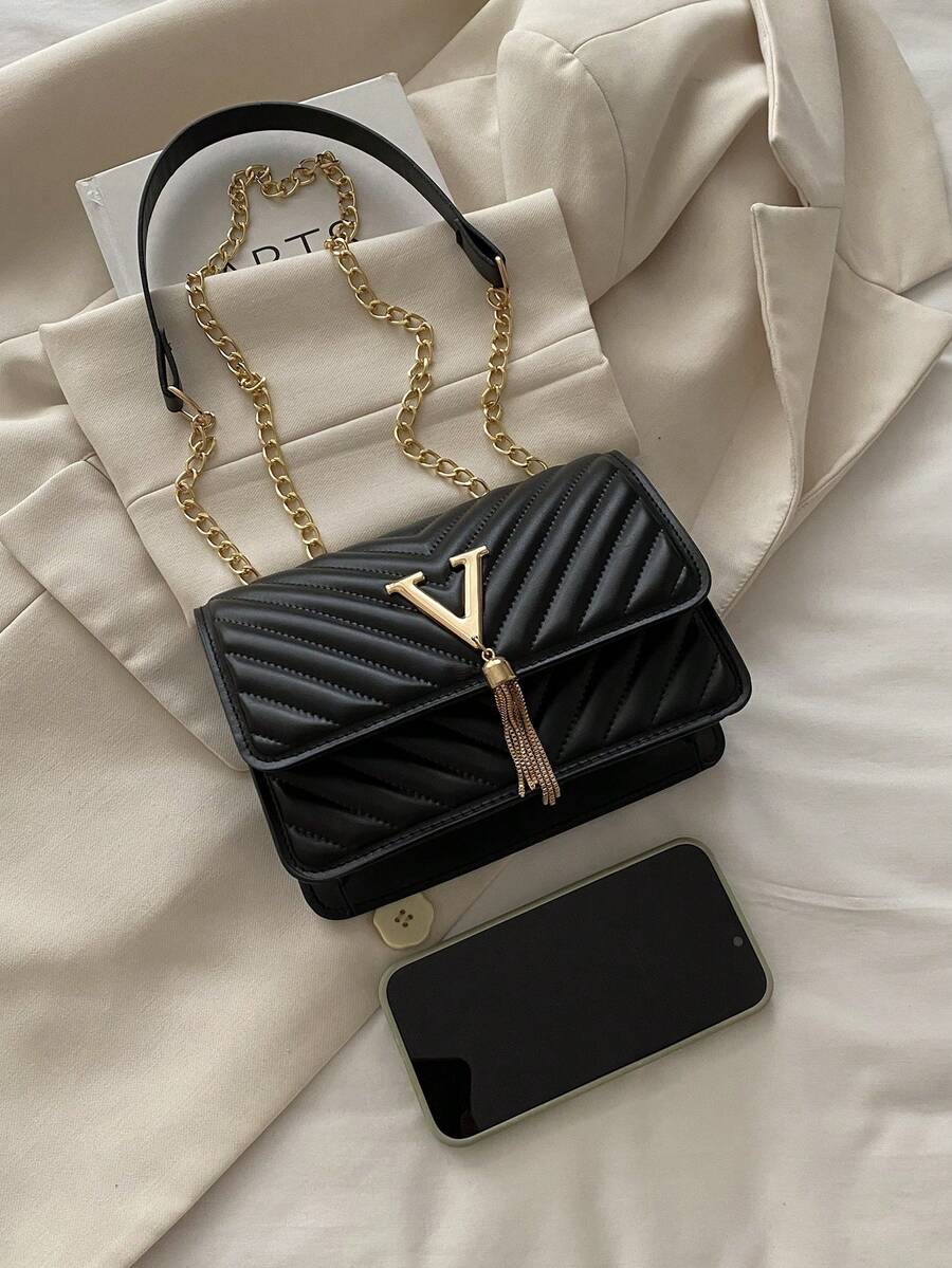 Refined Embossed Letter Shoulder Bag – New Year Collection with chain strap and tassel detail on a soft background.