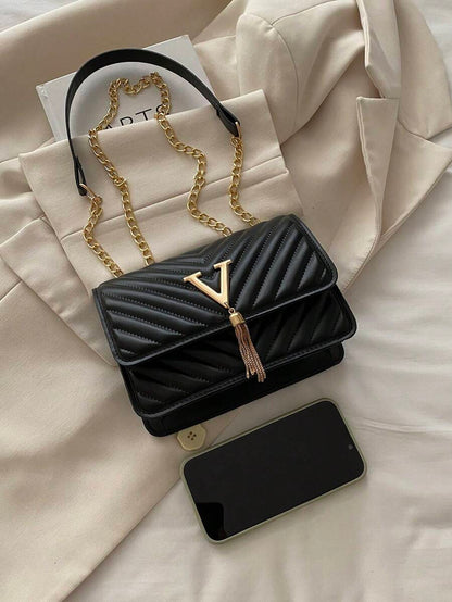Refined Embossed Letter Shoulder Bag – New Year Collection with chain strap and tassel detail on a soft background.