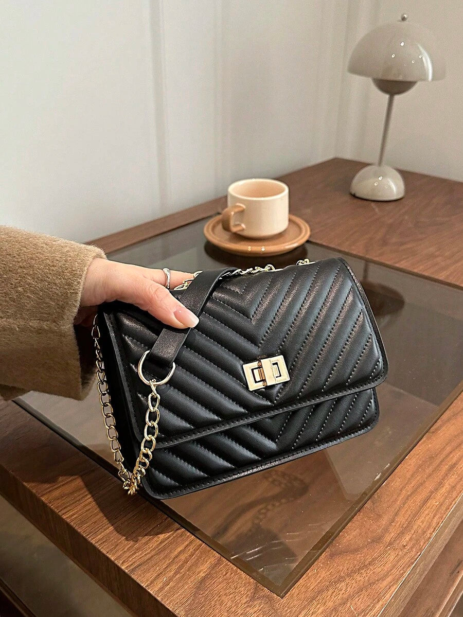 Refined Embossed Letter Shoulder Bag – New Year Collection displayed on a table, featuring elegant quilted design and chain strap.