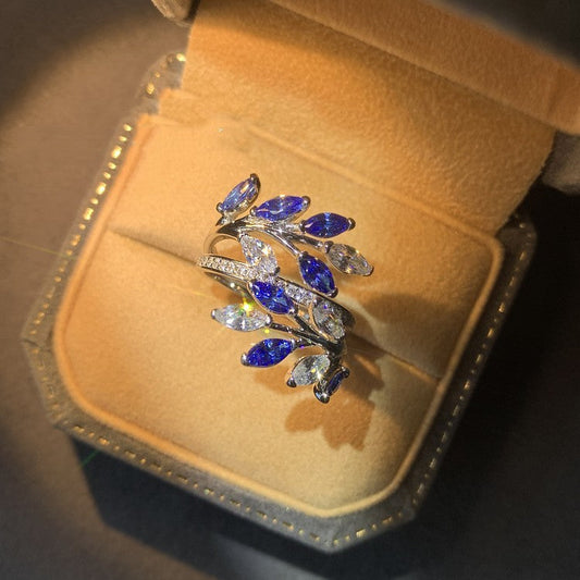 Elegant ring with blue and clear gemstones on a beige jewelry box