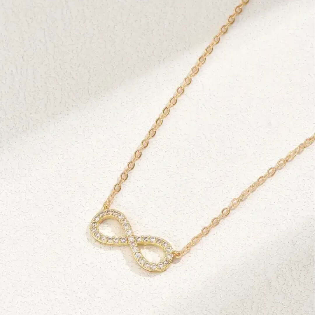 Gold infinity necklace on a light background