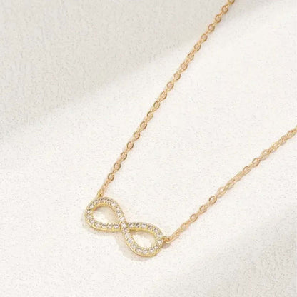 Gold infinity necklace on a light background