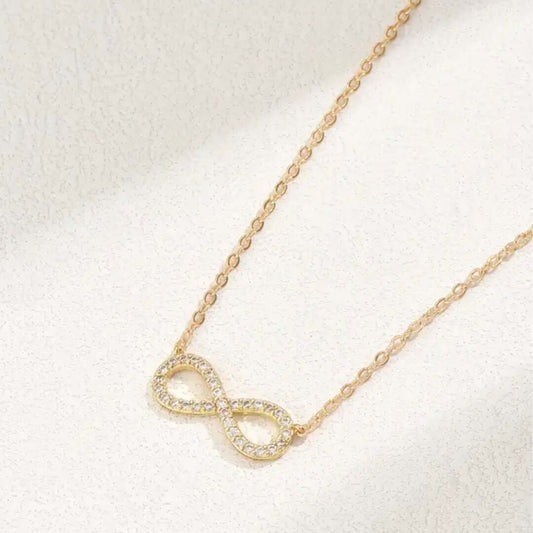 Gold infinity necklace on a light background