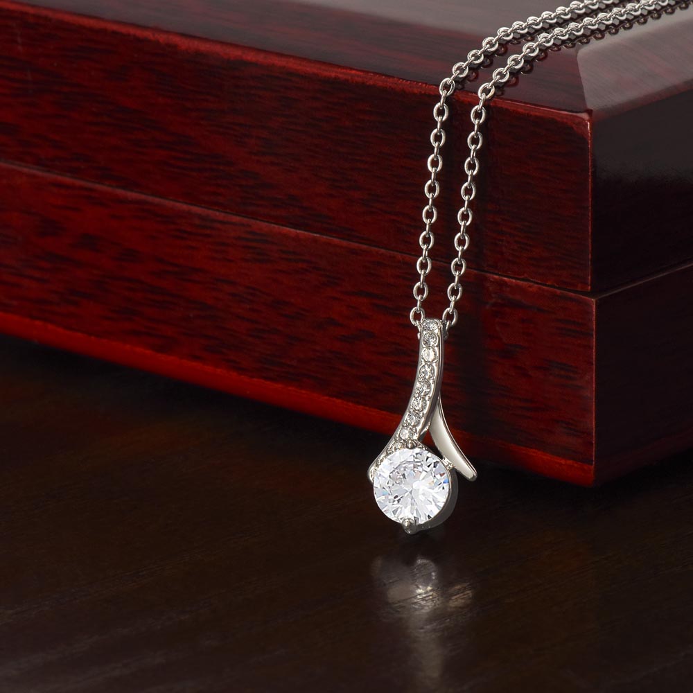 Forever Curve Love Necklace displayed on a wooden box, featuring a sparkling cubic zirconia pendant.